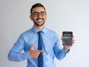 Smiling young man in office attire pointing at a calculator he is holding