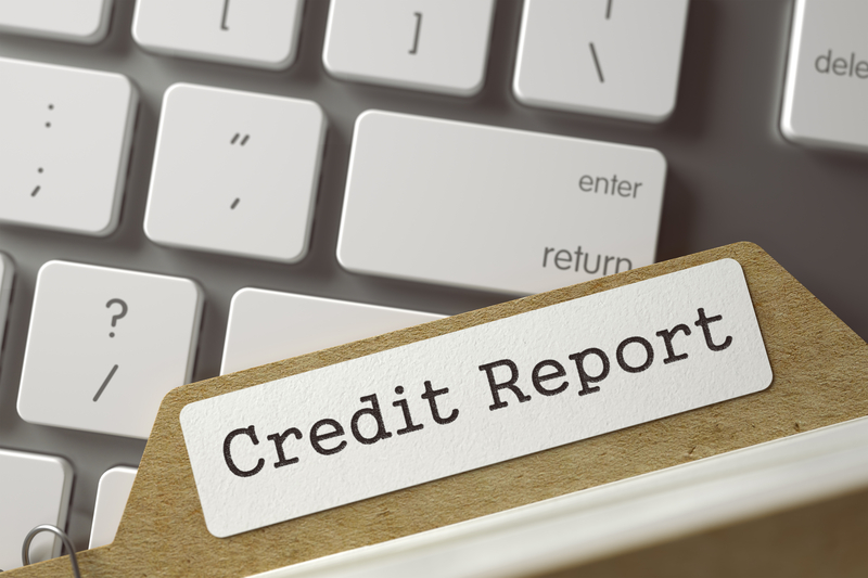 Against a Mac keyboard, a folder with a label that reads, “credit report”, depicting free credit report Singapore
