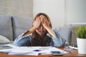 Young lady hiding her face due to financial stress, wondering if it’s possible to get a personal loan in Singapore with bad credit