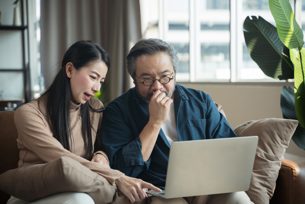 Stressed middle aged asian couple researching on laptop if it’s possible to get a personal loan without income proof in Singapore